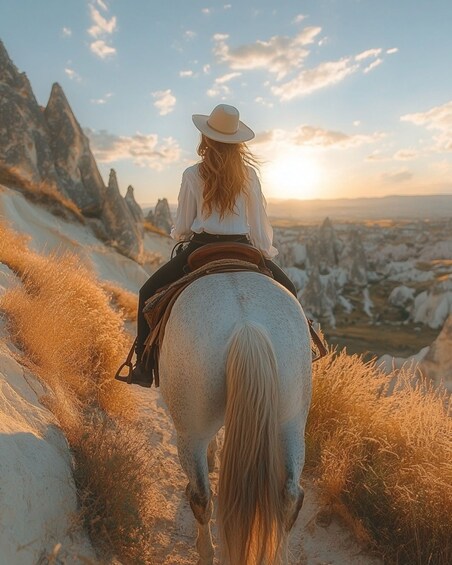 A person riding a horse on a mountain trail with a sunset in the background. 1