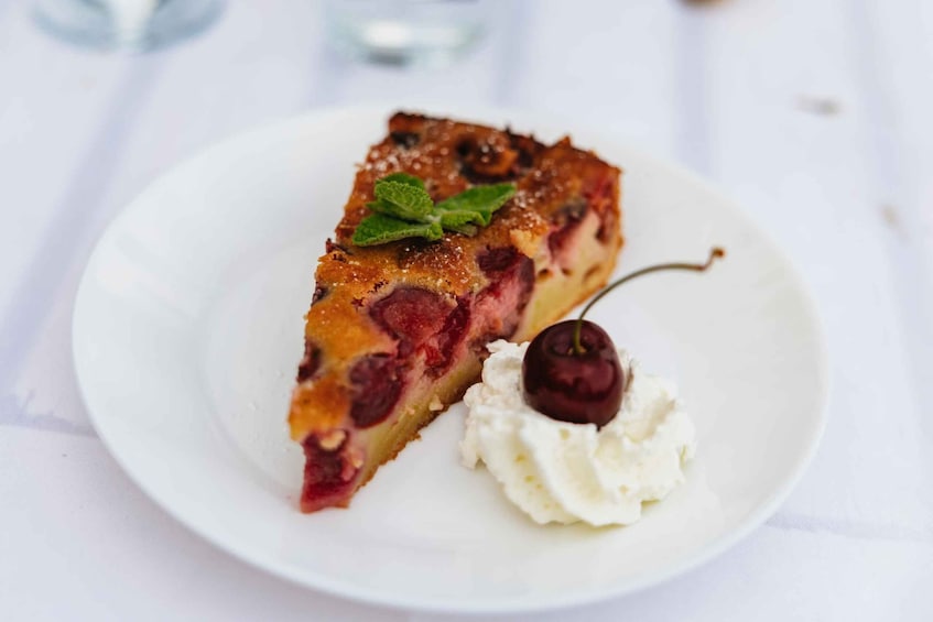 A slice of cherry pie on a white plate with whipped cream and a cherry on top. 4