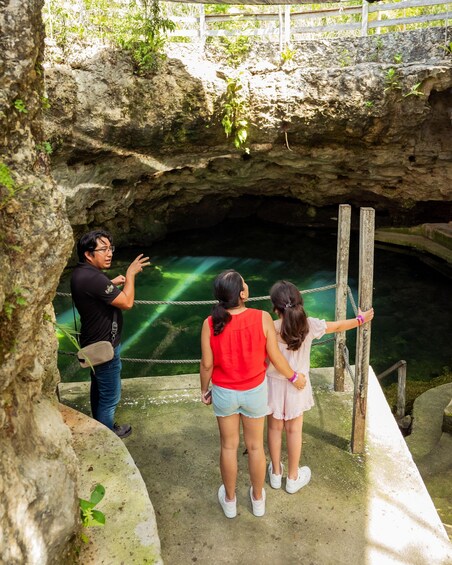 A family observing a cave with greenish water. 4