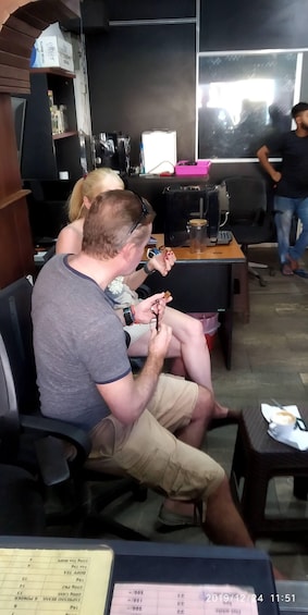 Two people seated at a table with a laptop, a coffee cup, and a clipboard. 5