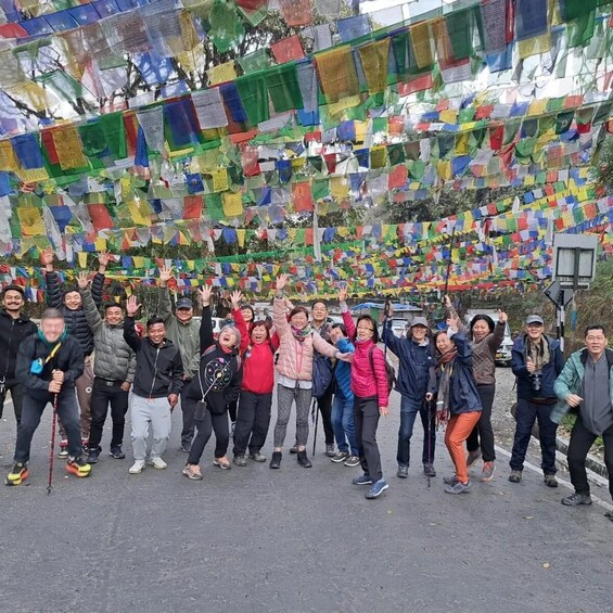A group of people standing in front of colorful prayer flags. 5