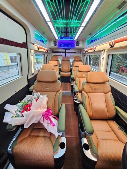 A train interior with leather seats, a central aisle, and overhead lighting. 4