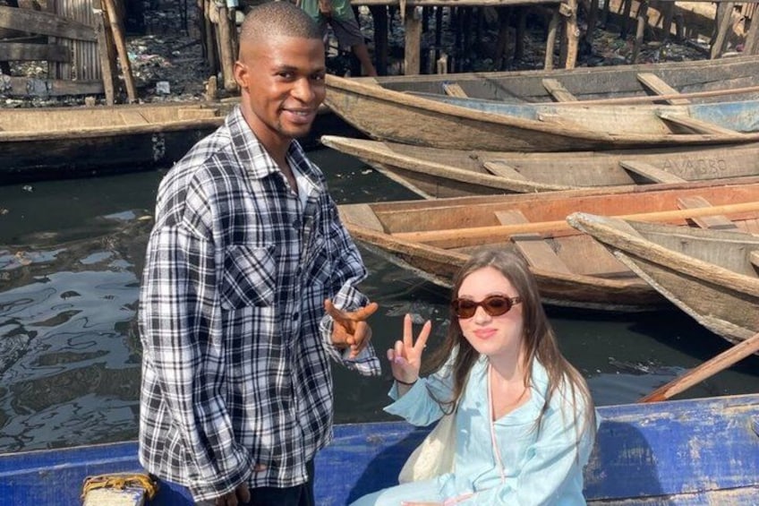 Two people on a boat with wooden boats in the background. 2