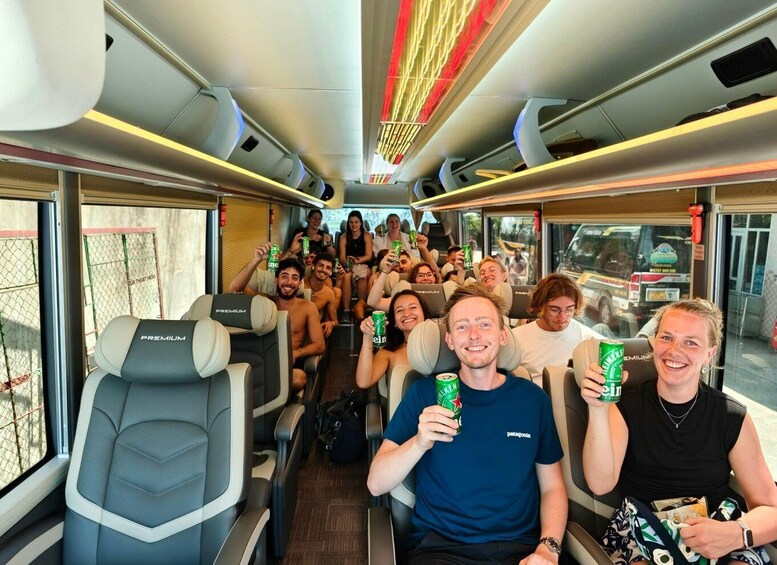A group of people on a train, holding green cans, likely beer. 1