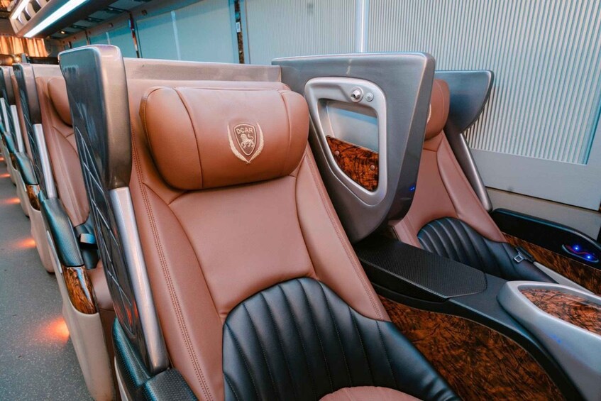 A luxury car interior with tan leather seats, a logo emblem, and a wooden accent on the door panel. 2