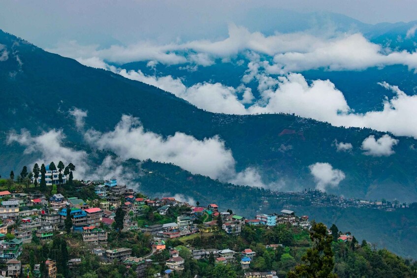 A mountainous village with houses nestled among lush greenery and clouds. 1