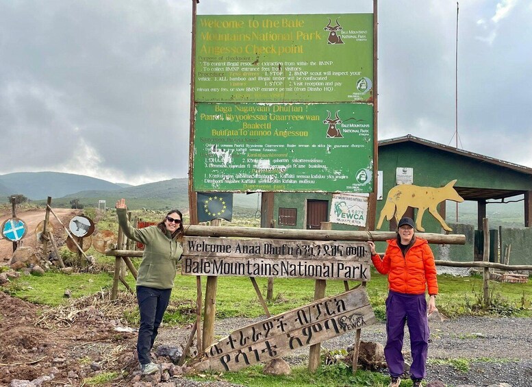 Two people standing in front of a signboard at Bale Mountains National Park. 1