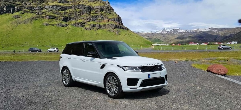 A white Range Rover SUV parked on a gravel road with a mountainous landscape in the background. 3