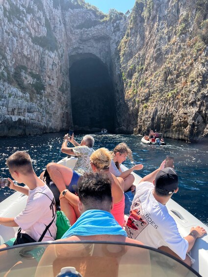 A group of people on a boat near a rocky cave entrance. 5