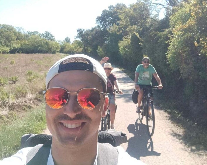 A person on a bicycle on a dirt path with greenery on both sides. 4