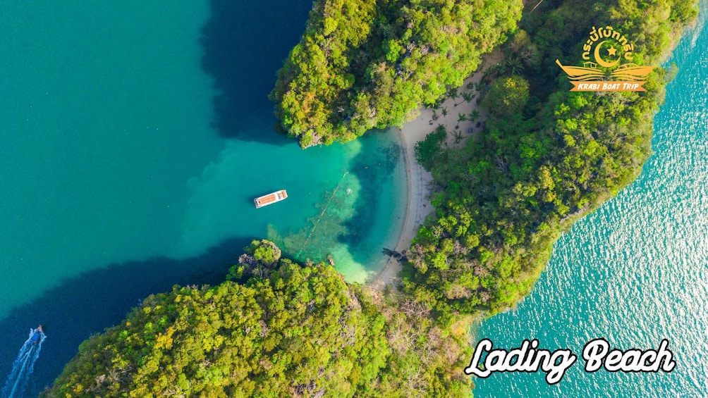 An aerial view of Lading Beach with clear turquoise waters, lush greenery, and a boat docked near the shore. 3
