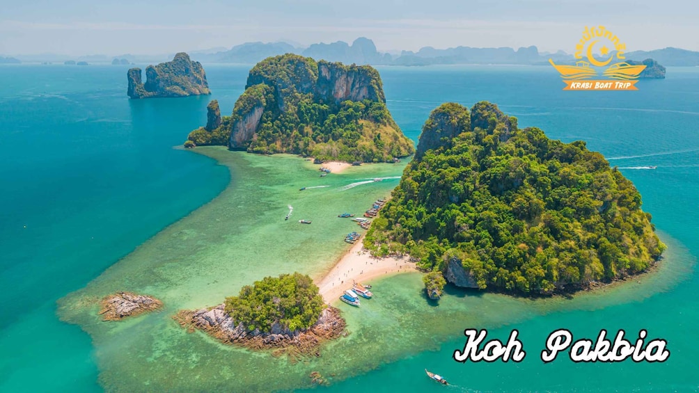 Koh Pakkia, a tropical island with clear turquoise waters, lush greenery, and a beach area. 2