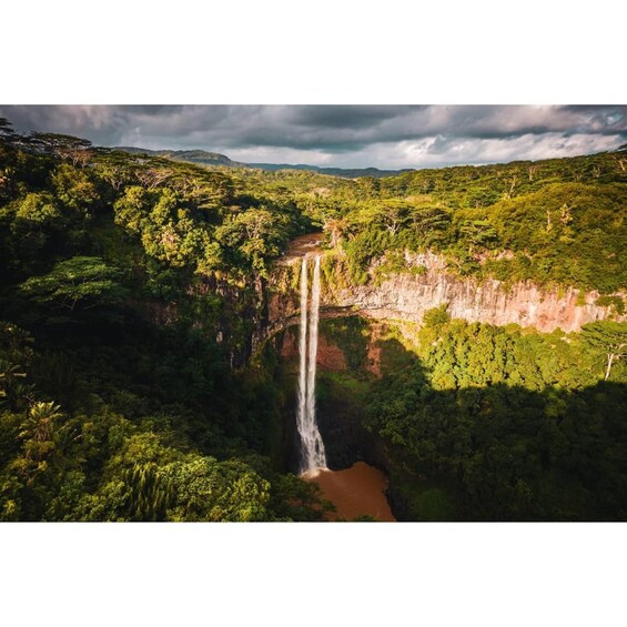 A waterfall cascading down a cliff surrounded by lush greenery. 2