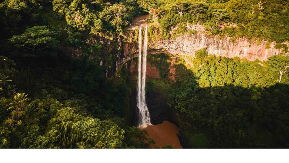 A waterfall cascading down a cliff surrounded by dense forest. 2