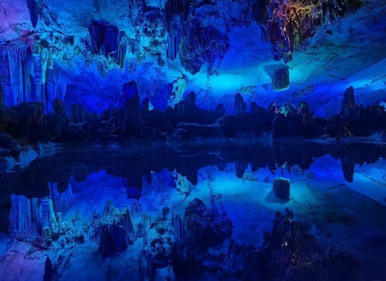 A cave with stalactites and stalagmites illuminated by blue lighting. 5