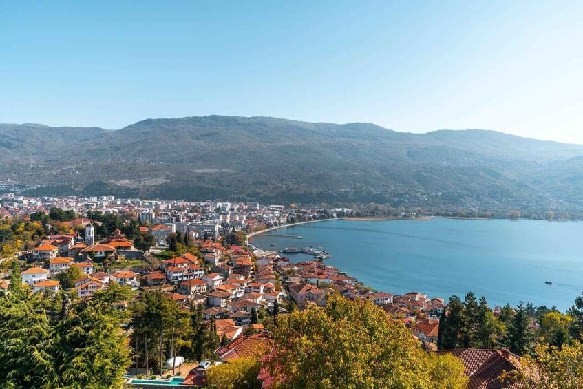 A coastal town with red-roofed houses, a bay, and mountains in the background. 5