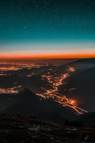 A starry night sky over a city with illuminated streets and distant mountains. 4