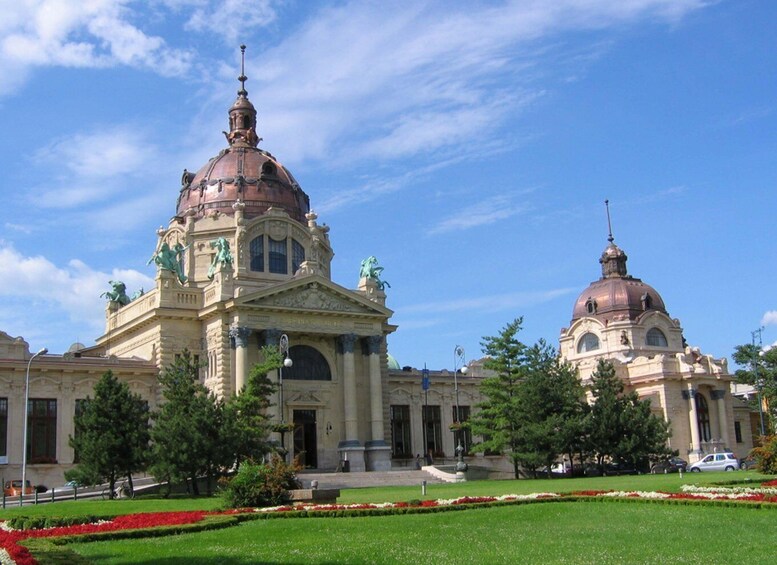 Un imposant bâtiment doté d’un grand dôme et de statues, entouré d’un jardin bien entretenu et surplombé d’un ciel d’un bleu éclatant. 4