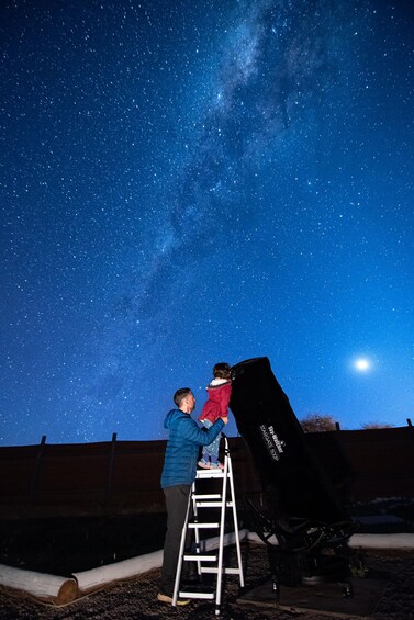Dos personas instalando un telescopio grande bajo un cielo estrellado. 2
