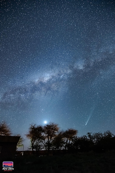 A starry night sky with the Milky Way visible, a bright moon, and a shooting star. 2
