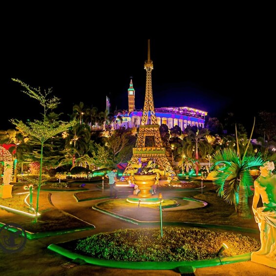 A brightly lit Eiffel Tower replica surrounded by a landscaped garden with palm trees and a fountain. 4