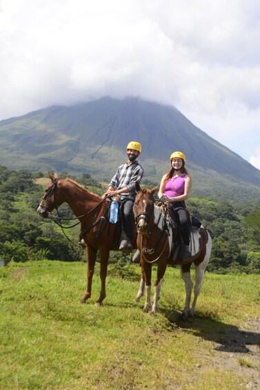 Two people on horseback with a mountain in the background. 3