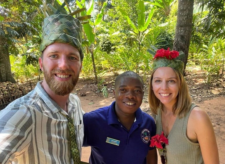 Three people in a tropical setting with dense green foliage and trees. 2