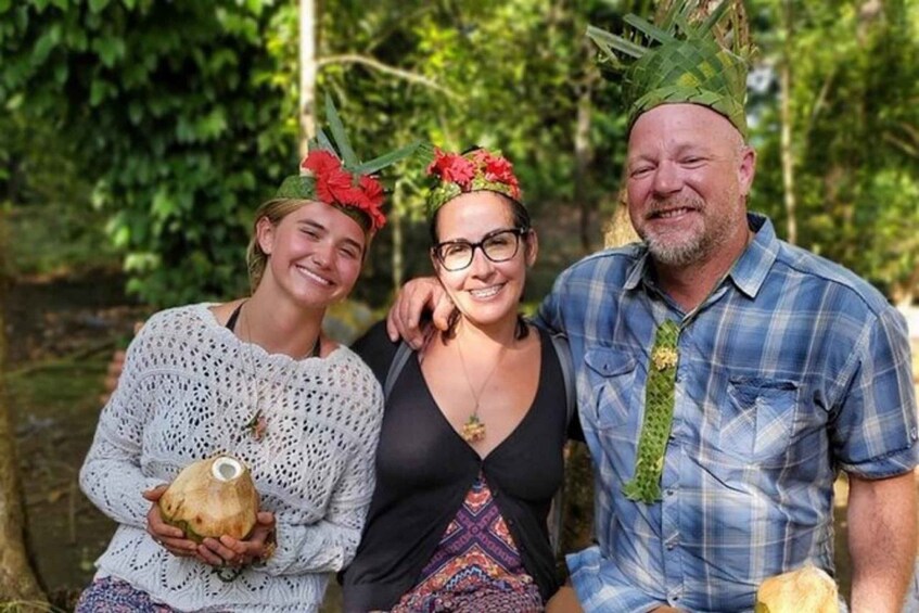 Three people outdoors, one holding a coconut. 1