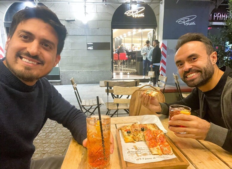 Two people sitting at a table with a pizza and drinks. 5