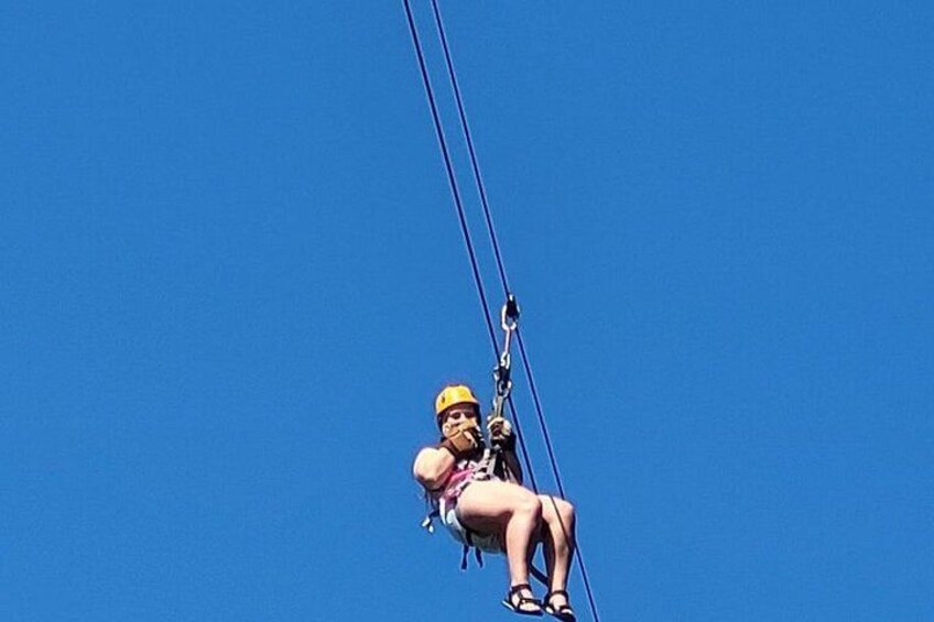 A person zip-lining against a clear blue sky. 3