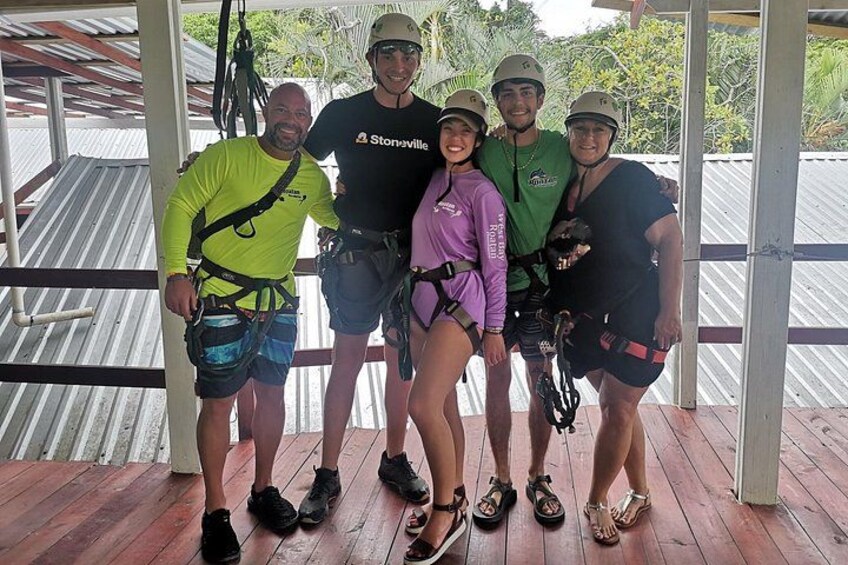 A group of people on a wooden deck with safety harnesses, indicating a zip-lining activity. 5