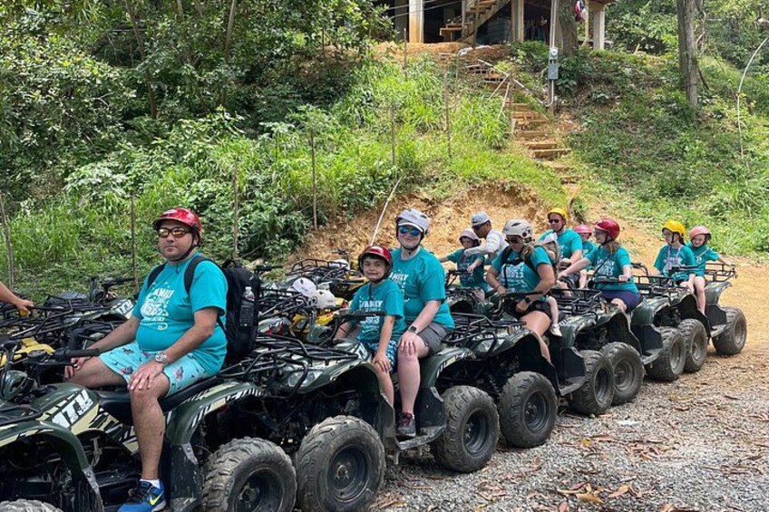A group of people on ATVs in a forested area with a dirt path and stairs leading up a hill. 1