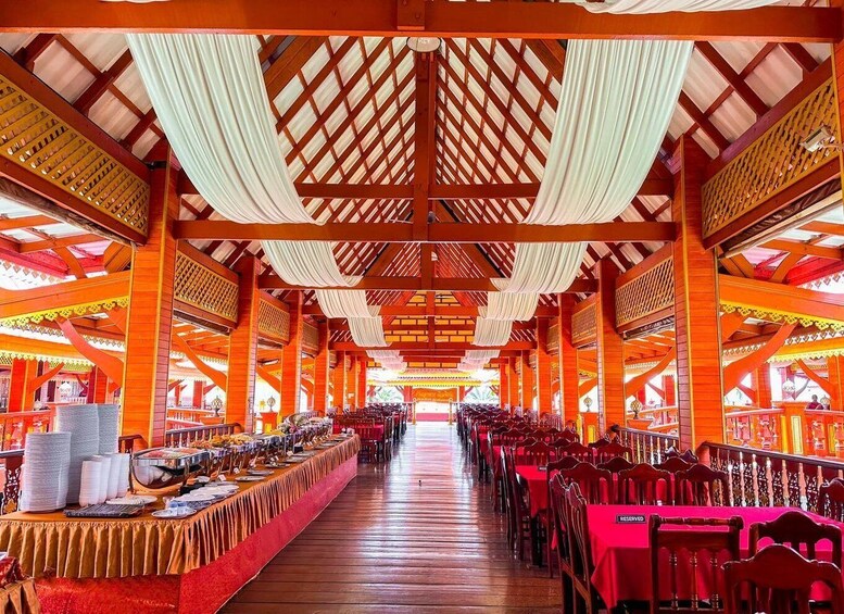 A long dining hall with red tables and chairs, white drapes hanging from the ceiling, and a wooden lattice design. 2