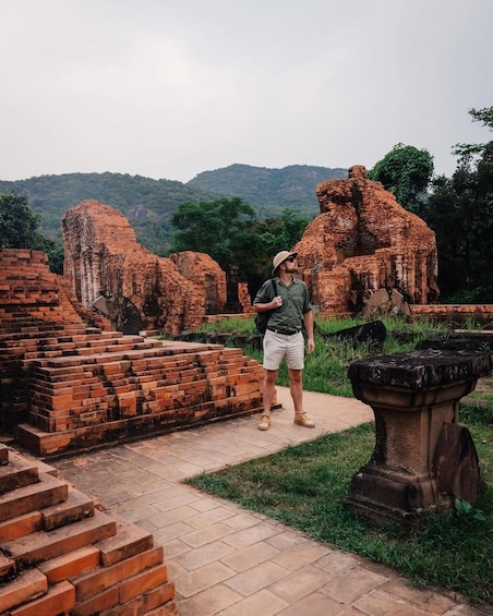 A person standing near ancient brick ruins with a mountainous landscape in the background. 3