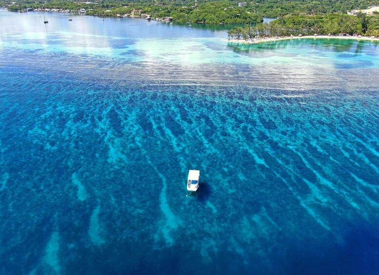 A boat on clear turquoise waters with a small island in the background. 1