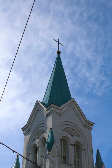A church with a green spire and a cross on top. 2