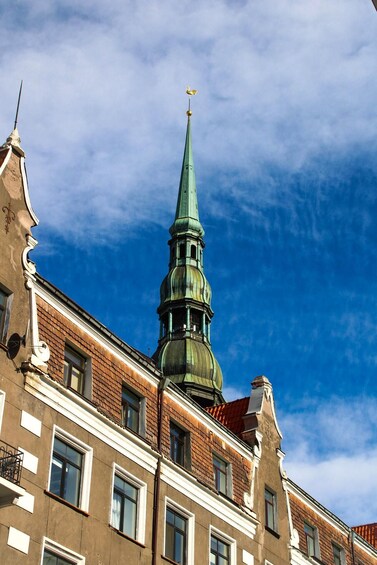 A church with a green spire and a golden finial against a blue sky. 5