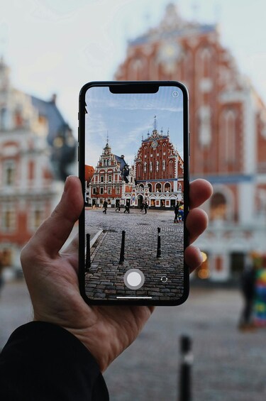 A hand holding a smartphone displaying a historic building with intricate architecture. 1