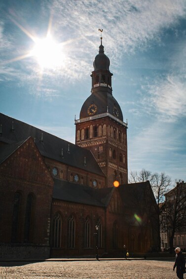 A historic building with a prominent clock tower and a dome, under a clear sky. 3