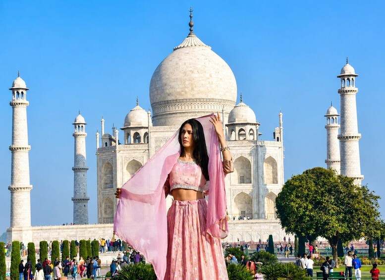 A person in traditional attire standing in front of the Taj Mahal with the iconic domes and minarets visible. 1