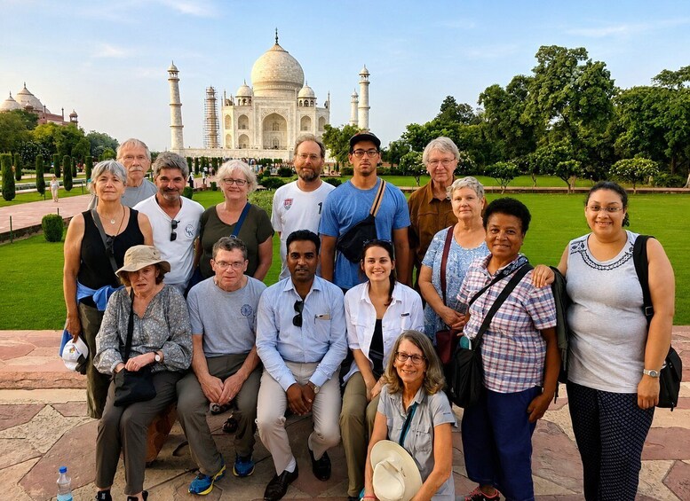 A group of people posing in front of the Taj Mahal with its domes and minarets visible in the background. 5