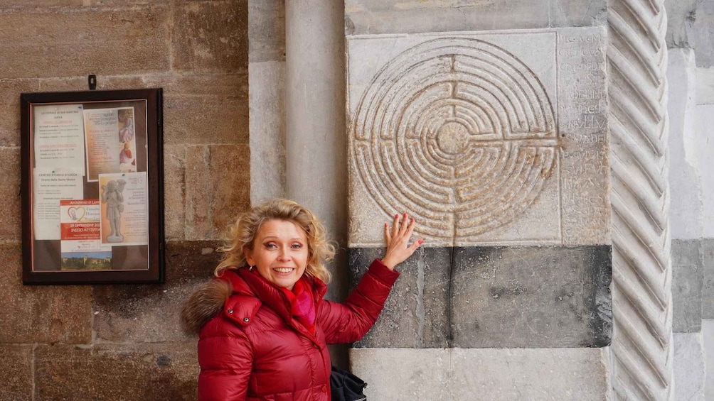 A person touching a stone relief with a circular design. 4