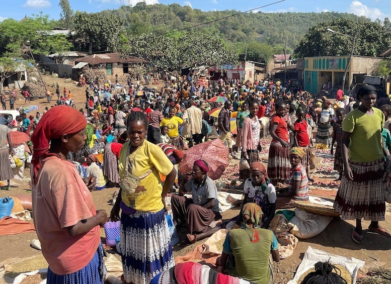 A crowded outdoor market with people selling and buying goods. 4