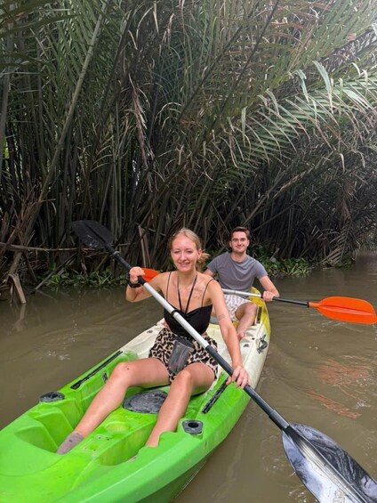 Two people kayaking through a river surrounded by dense vegetation. 5
