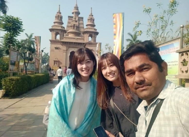 Three people posing in front of a historic building with multiple towers. 1