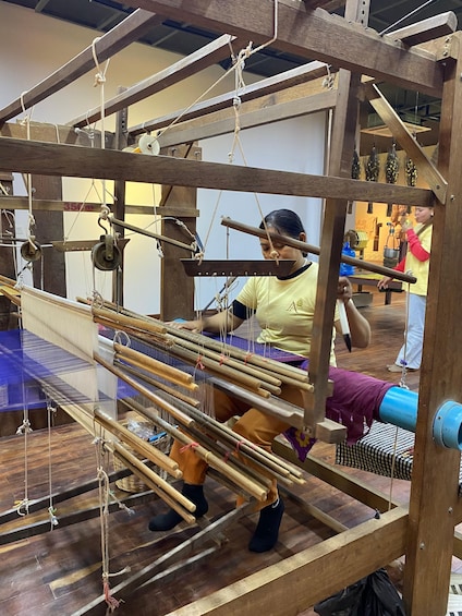 A person weaving on a traditional loom with wooden frames and ropes. 2