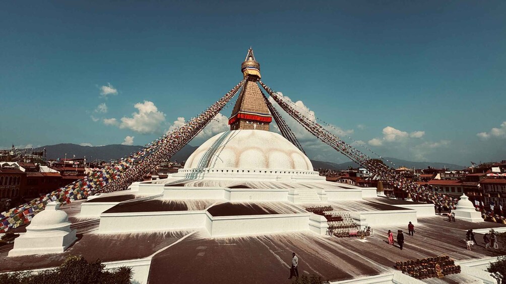 En stor, vit stupa med en gyllene topp, omgiven av böneflaggor. 1