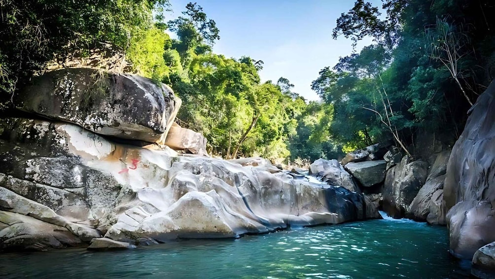 A river flowing through a rocky gorge with large boulders and dense green foliage. 1