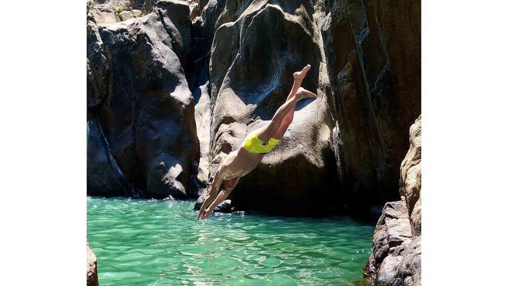 A person diving into clear water from a rocky cliff. 5
