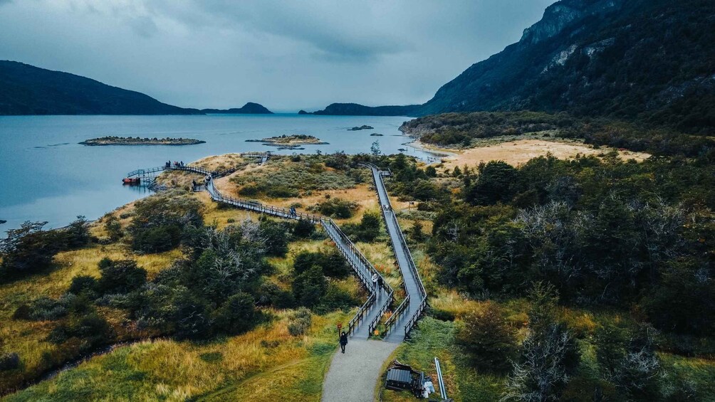 A winding boardwalk along a lake surrounded by hills and sparse vegetation. 1
